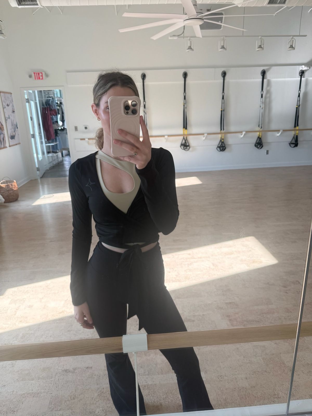 Model wearing the True40 black logo shrug tied at the waist in a fitness studio.