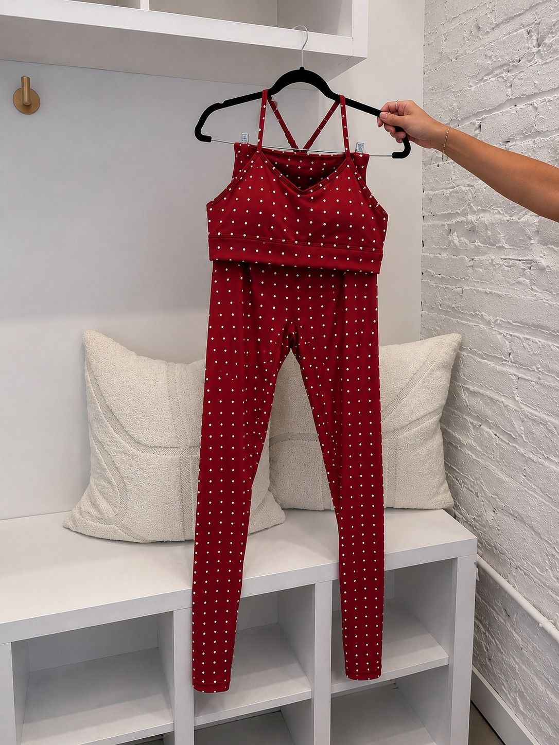 True40 red polka dot sports bra and matching leggings displayed together on a hanger.
